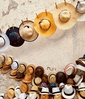 des chapeaux de pailles accrochés à des fils à linge contre un mur