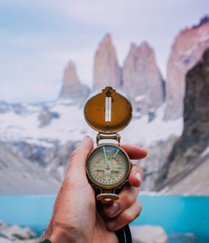 une main qui tient une boussole avec le parc Torres del Paine au chili en arrière plan