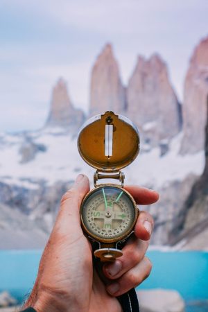 une main qui tient une boussole avec le parc Torres del Paine au chili en arrière plan
