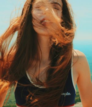 une femme sereine avec les cheveux au vent et la nature derrière elle