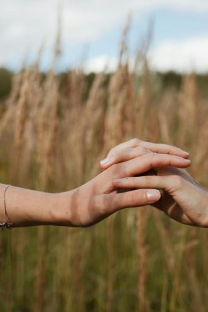 deux mains entrelacées dans un champ de blé